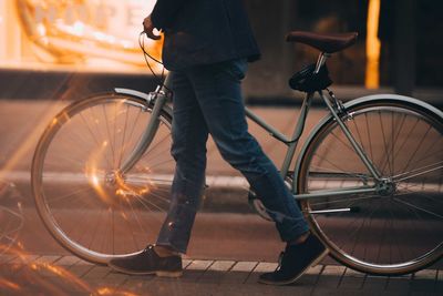 Low section of man with bicycle walking in city