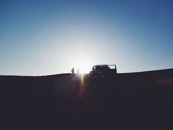 Women standing by off-road vehicle against blue sky