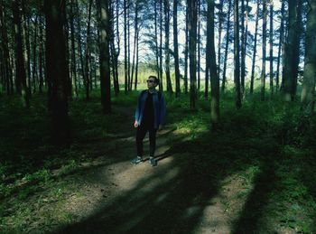 Full length of man standing on road in forest