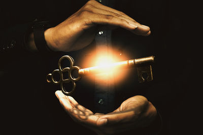 Close-up of hand holding candle against black background