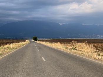Road leading towards mountains against sky