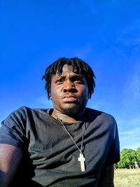 Portrait of man standing against blue sky