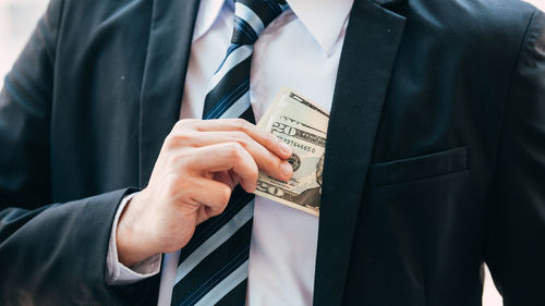 Midsection of businessman removing money from pocket