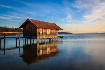 House on sea by building against blue sky