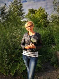 Portrait of young woman standing against plants