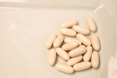 White gel capsules of vitamin co q-10 also called coenzyme q10 displayed on a white surface.