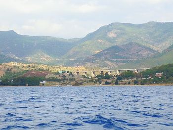 Scenic view of river by mountains against sky