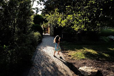 Rear view of woman walking on footpath amidst trees