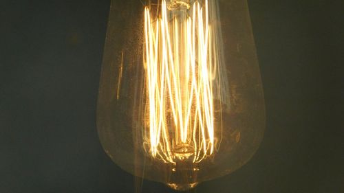 Low angle view of illuminated light bulb against black background