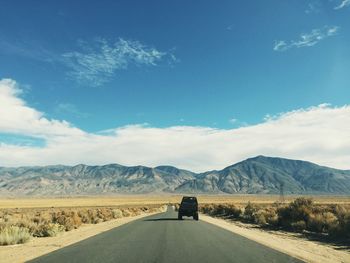 Off-road vehicle on country road leading towards rock mountains