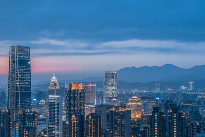 Illuminated modern buildings in city against sky