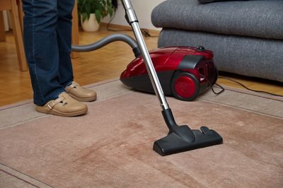 Woman using a vacuum cleaner while cleaning carpet in the house