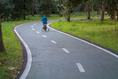 Rear view of man riding bicycle on road