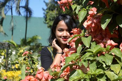 Portrait of smiling young woman against plants