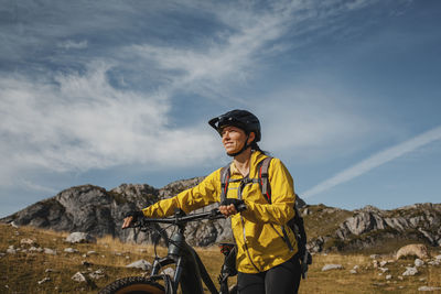 Smiling woman walking with electric mountain bike against mountain at somiedo natural park, spain