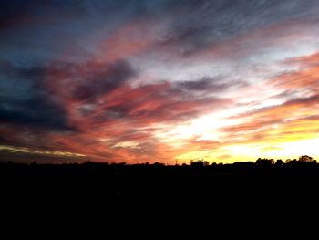 Silhouette landscape against dramatic sky during sunset