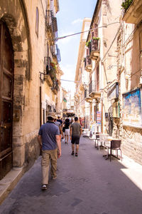 Rear view of people walking on street in city