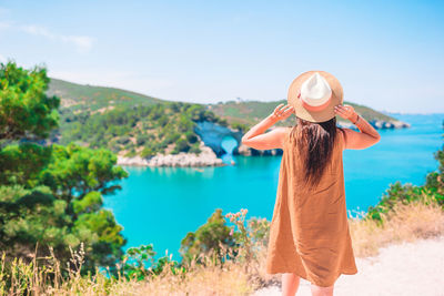 Woman standing on beach by sea against sky