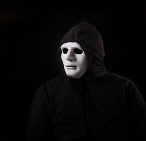Portrait of man wearing mask against black background