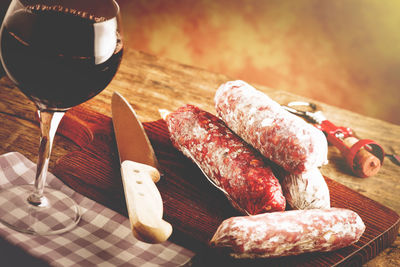 Close-up of red wine glass and salami on table