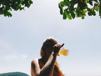 Woman holding food on plant against sky