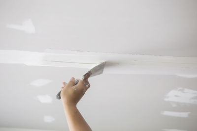 Cropped hand of person applying putty on wall