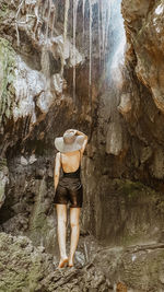 Rear view of woman standing on rock / waterfall view / woman standing in front of a waterfall