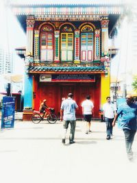 Rear view of people walking on street in city