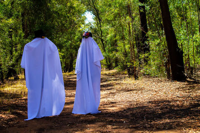 Rear view of people walking on field in forest
