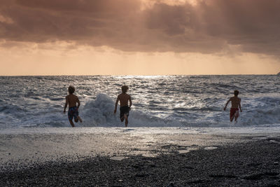 People on beach against sky during sunset