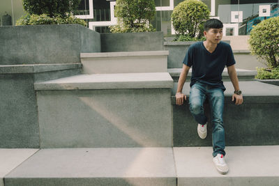 Full length of young man sitting outdoors