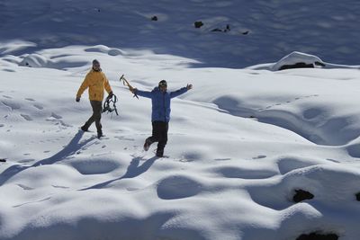 Portrait of friends with equipment walking on snowcapped mountain