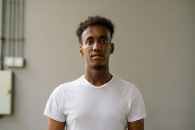 Portrait of young man standing against wall