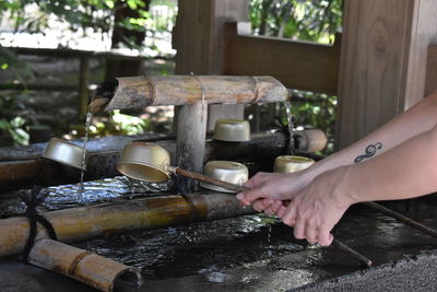 Cropped hand holding ladle at drinking fountain