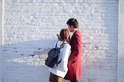 Couple standing against brick wall