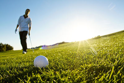 Man standing on golf field against clear sky