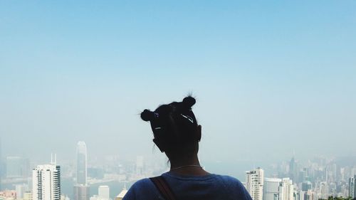 Rear view of woman looking at city against clear sky