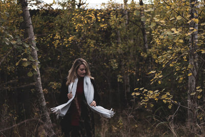 Woman standing by tree in forest