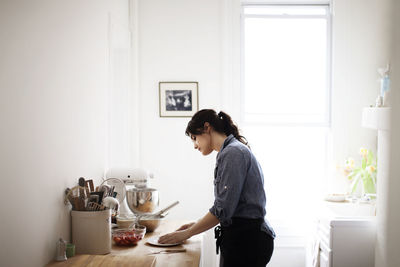 Side view of woman preparing food at home