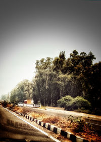 Road by trees against clear sky