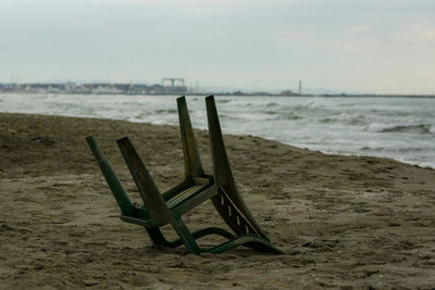 Wooden posts on sandy beach against sky
