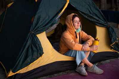 Full length of young woman sitting on tent