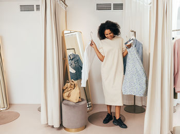 Smiling woman trying dress at clothing store