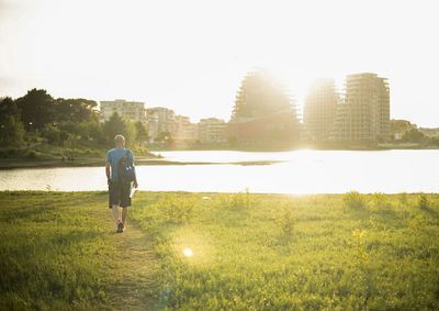 Rear view of man walking on field against sky