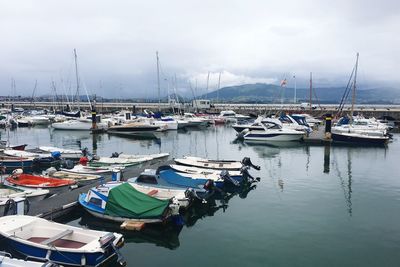 Boats moored at harbor against sky