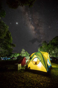 Tent and trees against sky at night