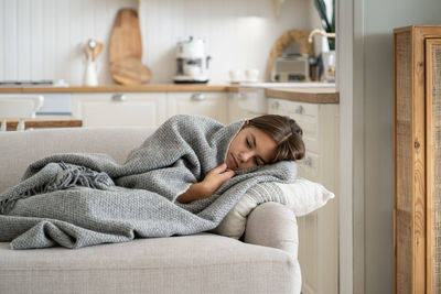 Portrait of young woman sitting on sofa at home