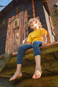 Girl plays in creative handmade treehouse in backyard, summer activity, happy childhood, cottagecore