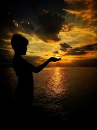 Silhouette person standing on beach against sky during sunset
