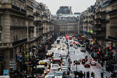 Vehicles on street amidst building at dusk